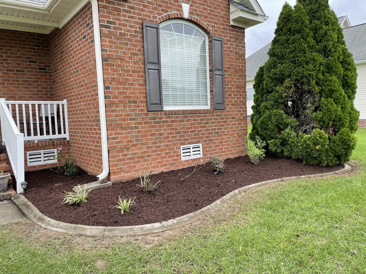 Fresh mulch bed with curved edging along a brick home foundation