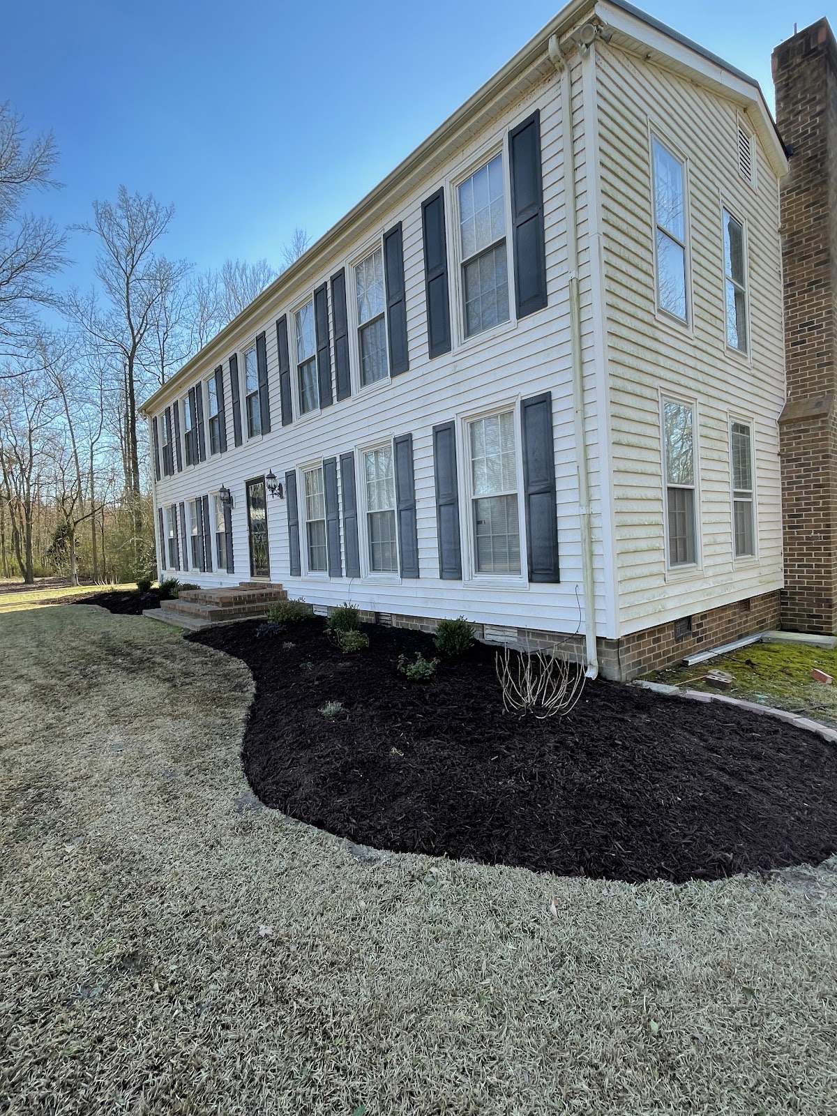 New mulch beds and gravel around a two-story white house